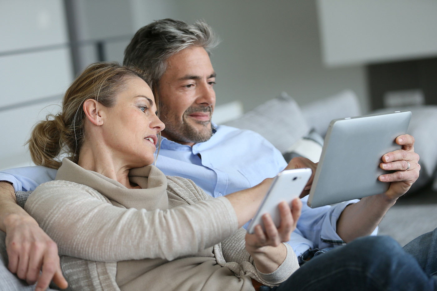 Couple using a smartphone and tablet to view their online home inspection report